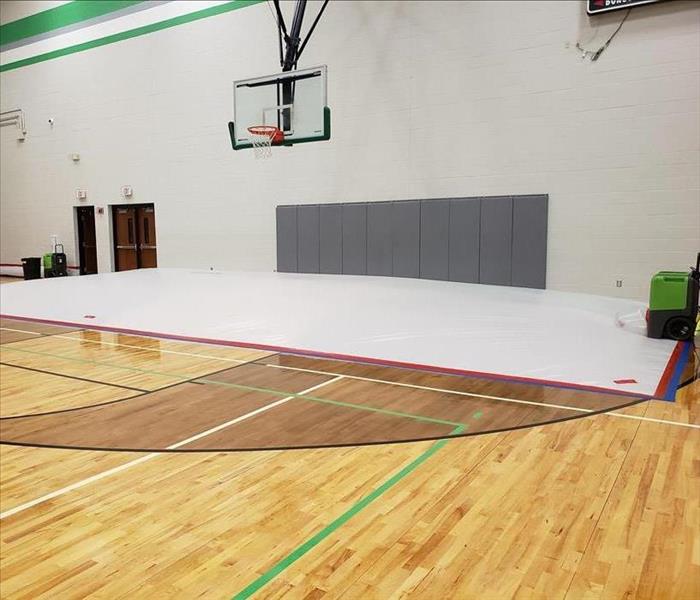 School gymnasium with part of the wood floor covered with a white tarp.