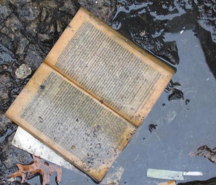 An open book submerged in a puddle and dirty.