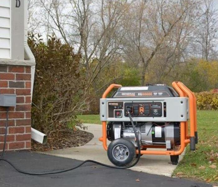 A generator is plugged into an outdoor outlet on a house
